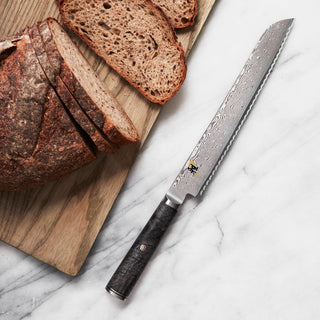Miyabi Black 5000 9.5-inch bread knife with a sharp, serrated edge and black handle, ideal for slicing bread and baked goods.