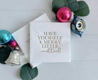 Gold cocktail napkins with "Have Yourself a Merry Little" printed design, perfect for festive gatherings.