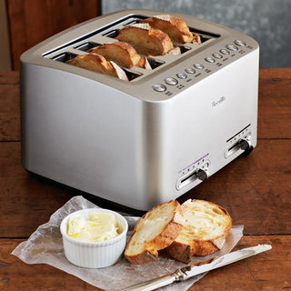Breville Die-Cast 4-Slice Smart Toaster with stainless steel finish, shown with toasted bread slices on a countertop.