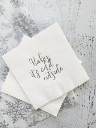Silver cocktail napkins featuring "Baby, It's Cold Outside" design by EnFete, LLC, with festive winter-themed print.